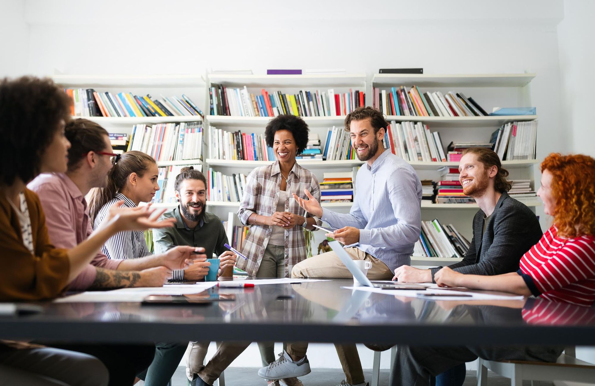 An age-diverse coworking team enjoy a meeting together as they share insights.