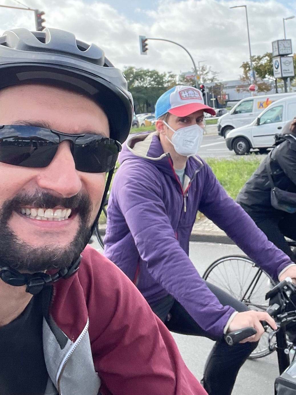 Alex and Thilo, who are co-founders of Cobot, smile at the camera while riding their bicycles in the demonstration. 