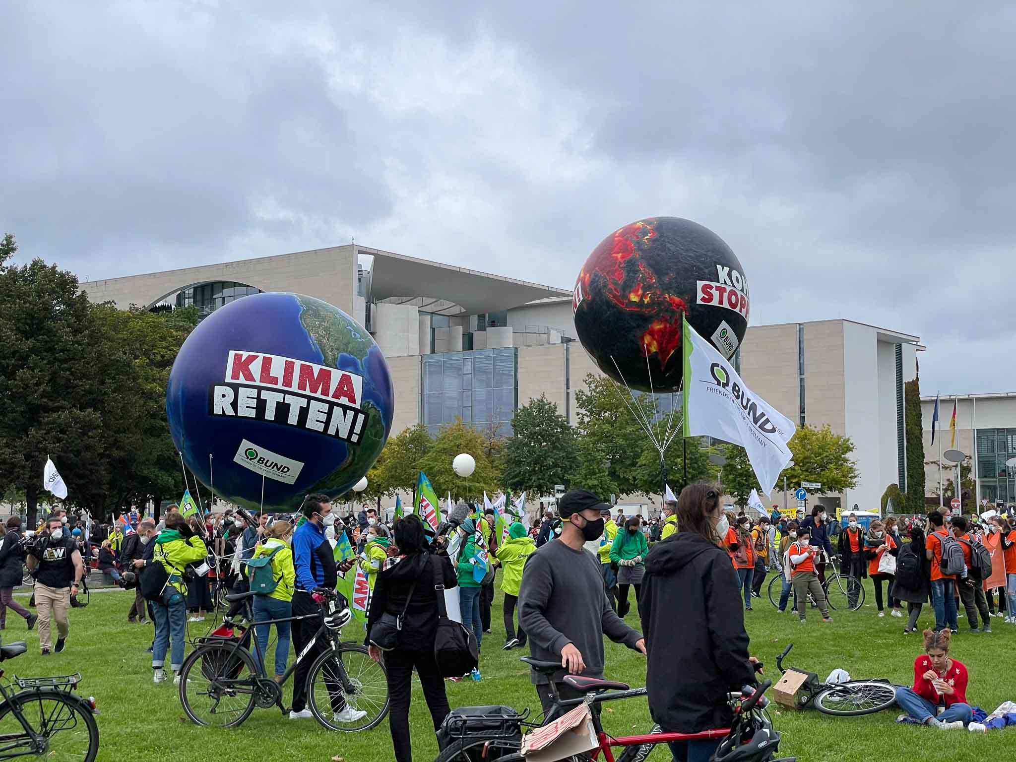 Berliners—including members of the Cobot team—gather in the grass front of the German parliament with their bicycles, placards, and balloons that say “Klima Retten!”