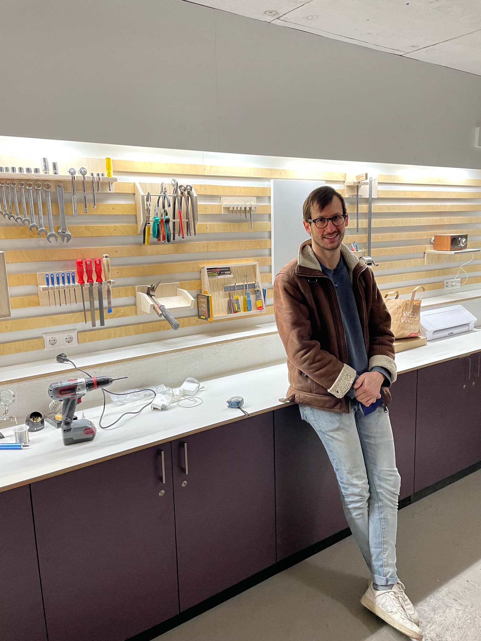 Lenny Leiter, workish’s founder and manager, leans against a workbench in the space. Visible behind him are the custom shelves onto which a myriad of tools fit perfectly.