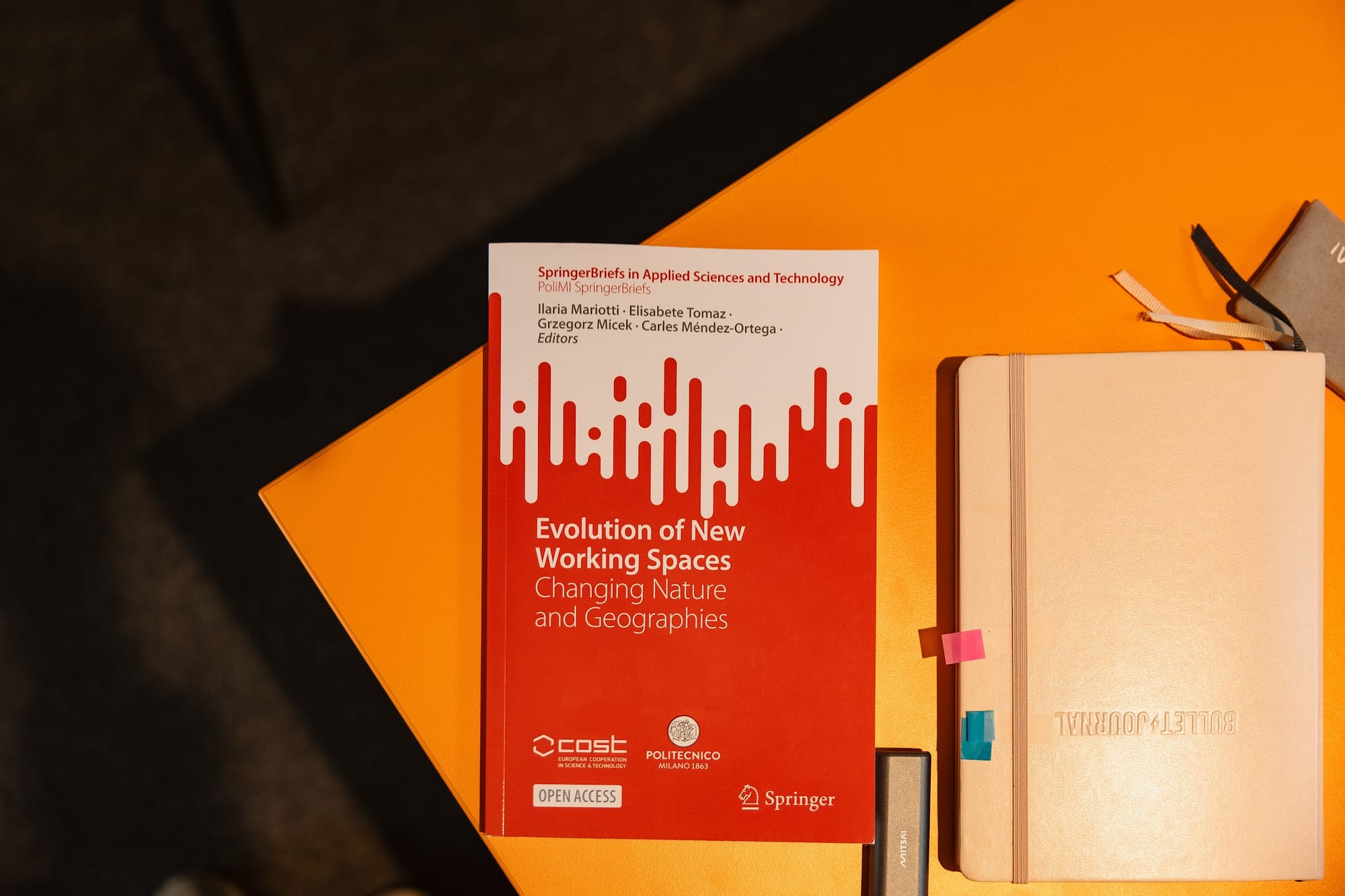 Evolution of New Working Spaces" book cover placed on a wooden table, featuring a modern office setting