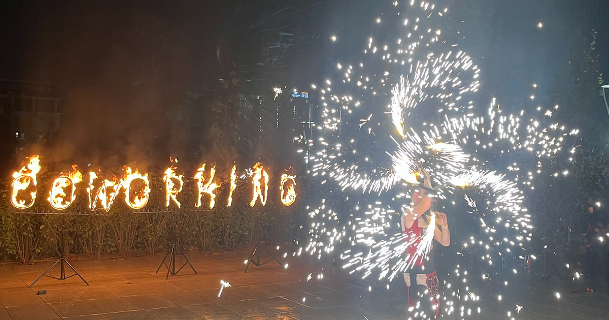 Coworking sign on fire with firethrowers next to it